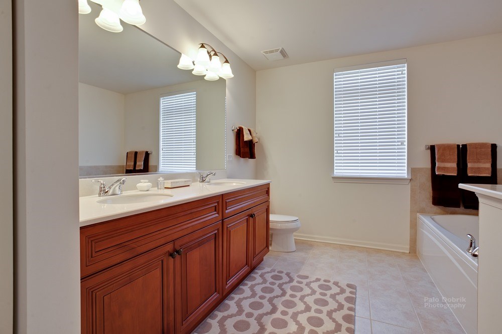 bathroom in an apartment building condo with double sink vanity on the left and bathtub on the right