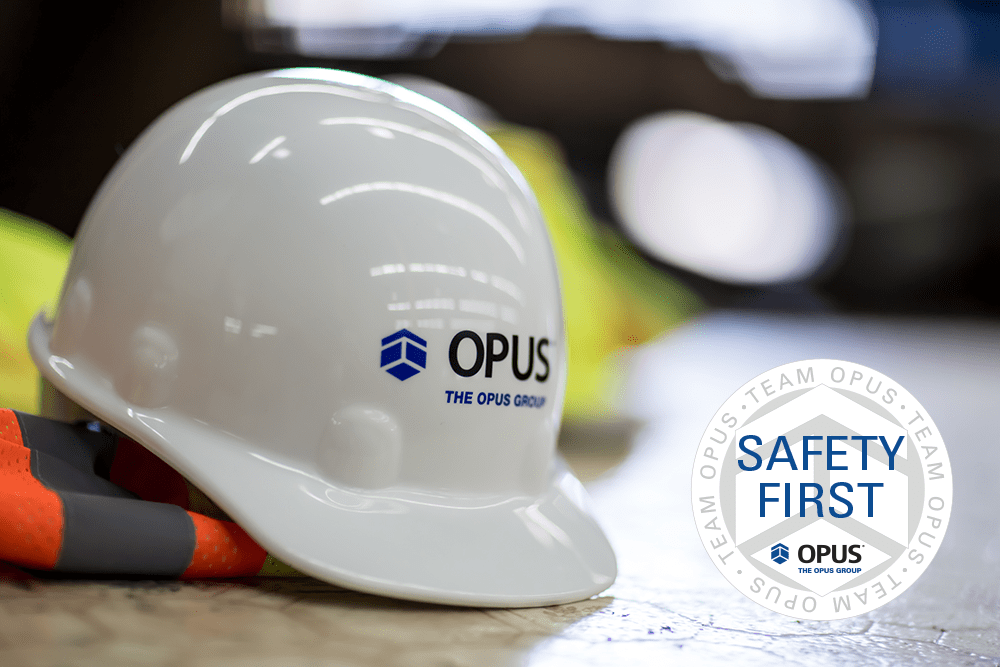 A hard hat with The Opus Group on the front with a badge over the image that says Safety First.