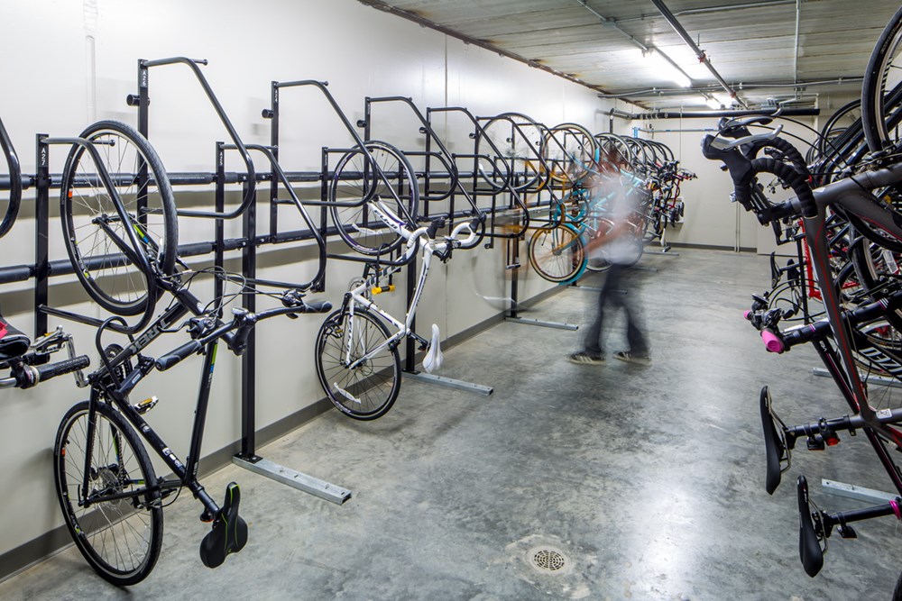 bicycle storage area in an apartment building with several bicycles hanging vertically on the wall in racks