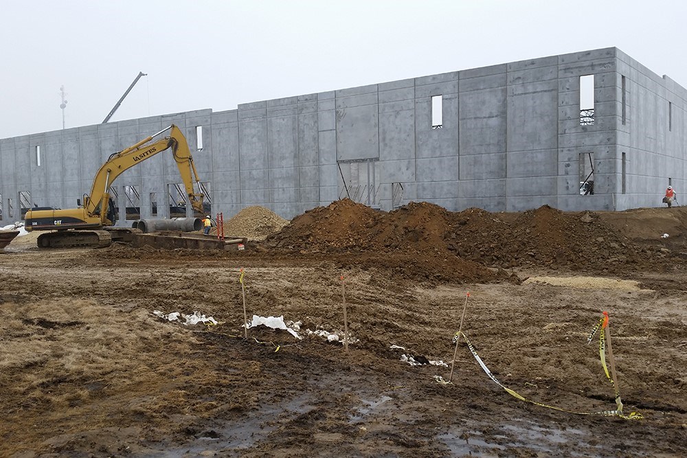 construction image of the shell exterior of an industrial building with heavy equipment and piles of dirt in the foreground