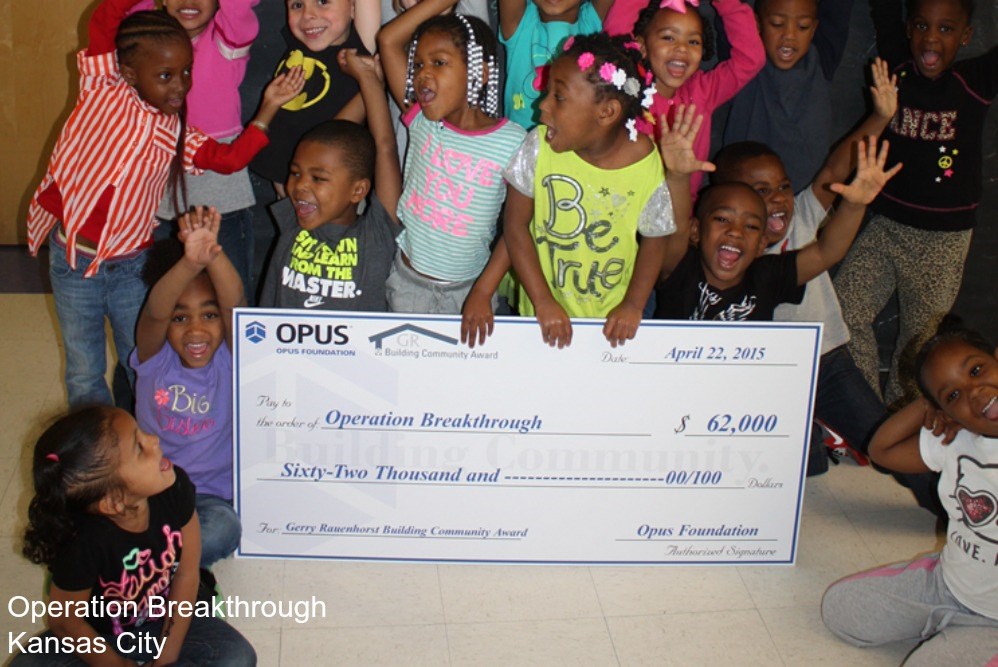 a group of children holding a large check for $62,000 for Gerry Rauenhorst Building Community Award winner Operation Breakthrough from the Opus Foundaton