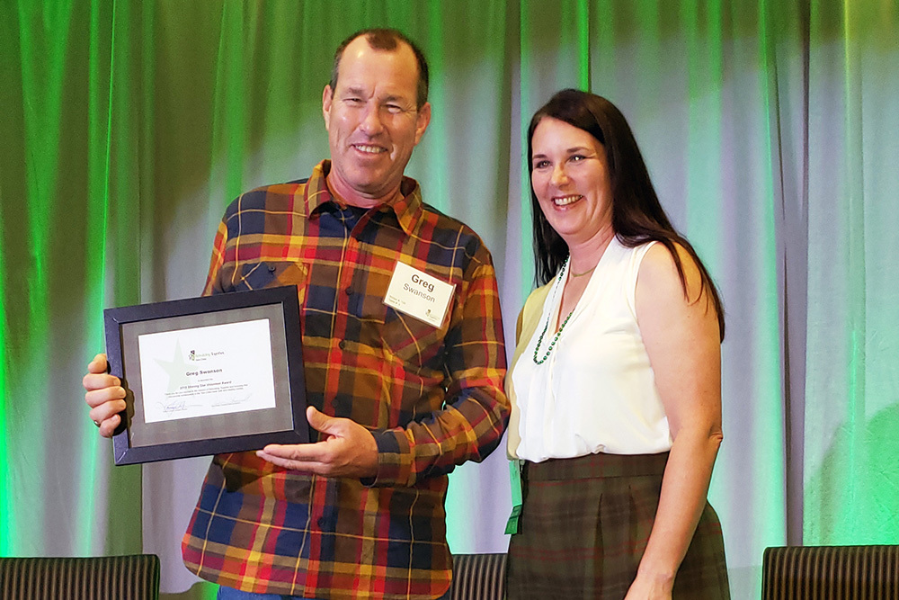 Greg Swanson receives his Shining Star volunteer award from Rebuilding Together Twin Cities Executive Director Kathy Greiner