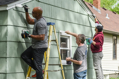 Men on ladders painting exterior of house
