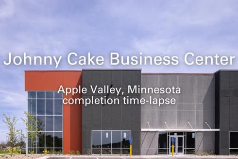 exterior of entrance of industrial building with the words "Johnny Cake Business Center, Apple Valley, Minnesota, completion time-lapse" in foreground