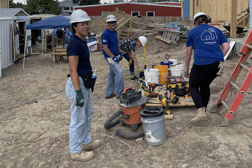 men and women wearing blue shirts and hard hats on a construction site