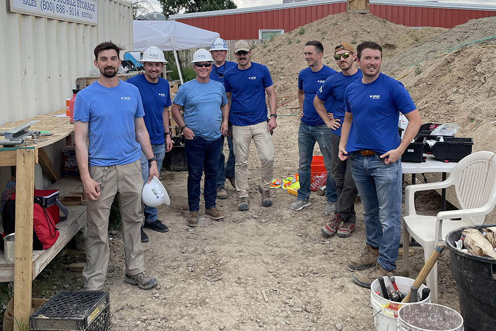 group of men wearing blue shirts and some wearing hard hats standing on a construction site