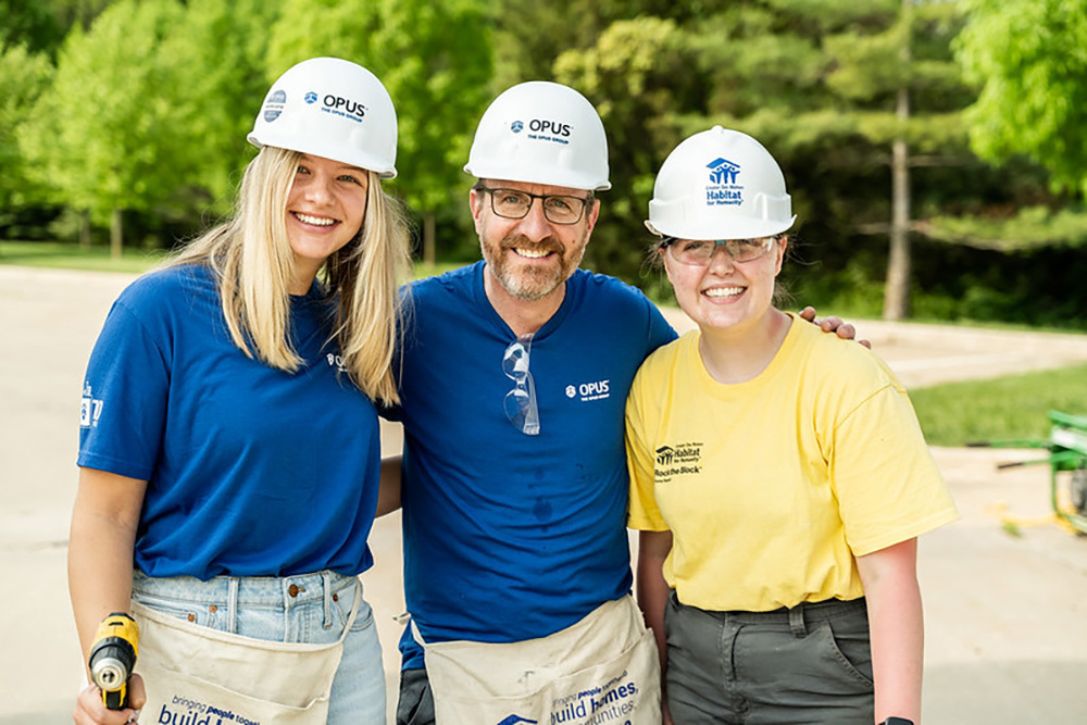 two women and a man wearing hard hats