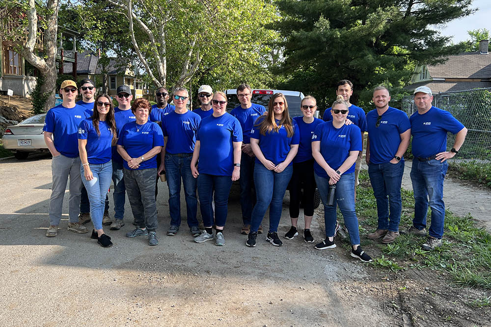 group of men and women wearing blue shirts standing outside