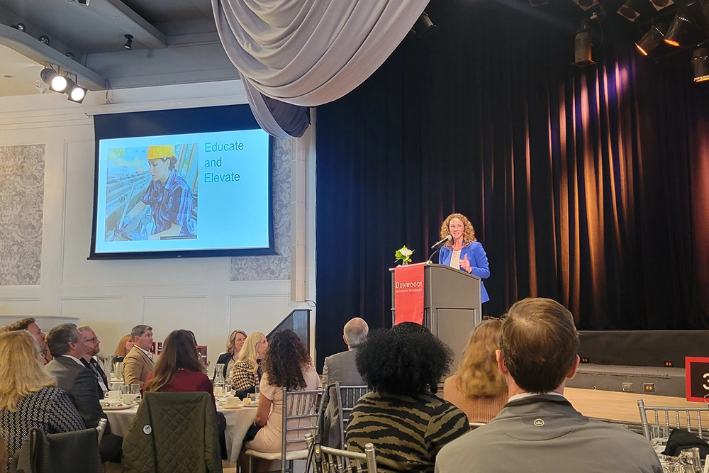 woman at podium on stage speaking to audience