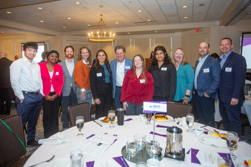 group of men and women standing behind table