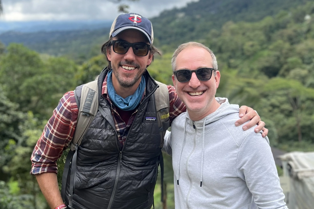 two smiling men standing outside