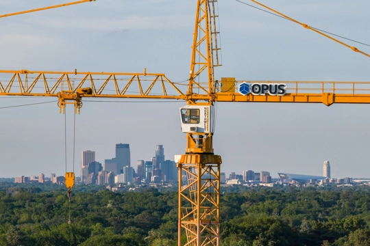 crane with banner reading Opus in foreground with city skyline in background