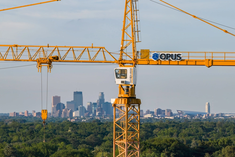 crane with banner reading Opus in foreground with city skyline in background