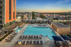 aerial view of the rooftop swimming pool and outdoor living area of an apartment building with a view of the city in the background