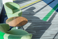 detailed view of a seating area inside an office building with two green chairs around a small, round end table