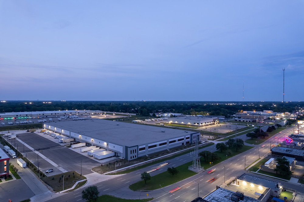 aerial view of back of industrial building showing dock doors and parking lot at sunset