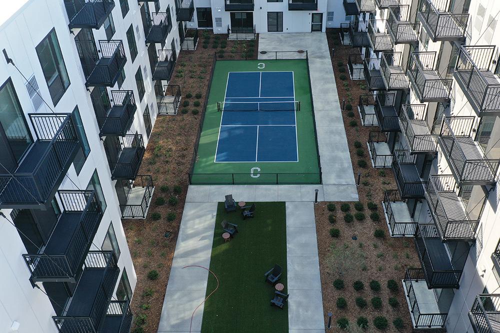 aerial view of an apartment building's courtyard outdoor amenity area including tennis court