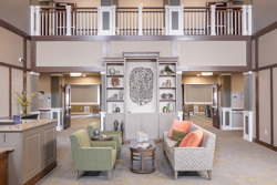 lobby of a senior living building with a seating area in the foreground and shelving unit in the background