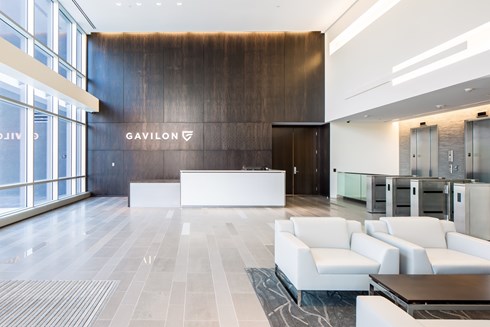 lobby of an office building with coffee table and chairs in foreground on right and reception desk in the background