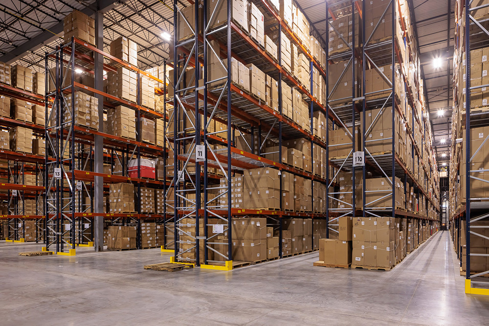 warehouse in an industrial building with rows of tall shelves filled with boxes