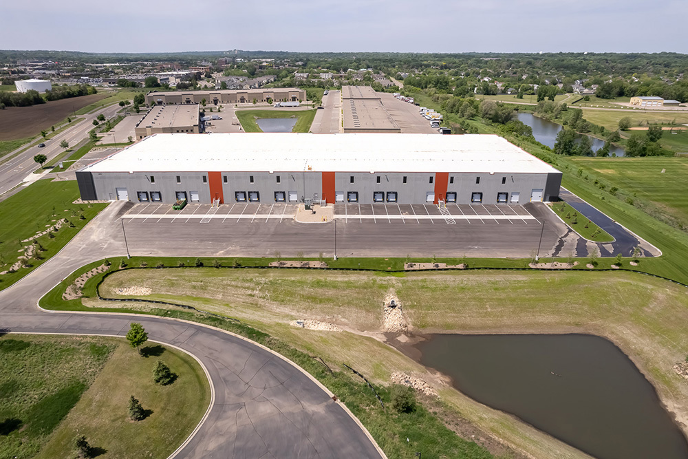 aerial view of back of industrial building showing dock doors and parking lot