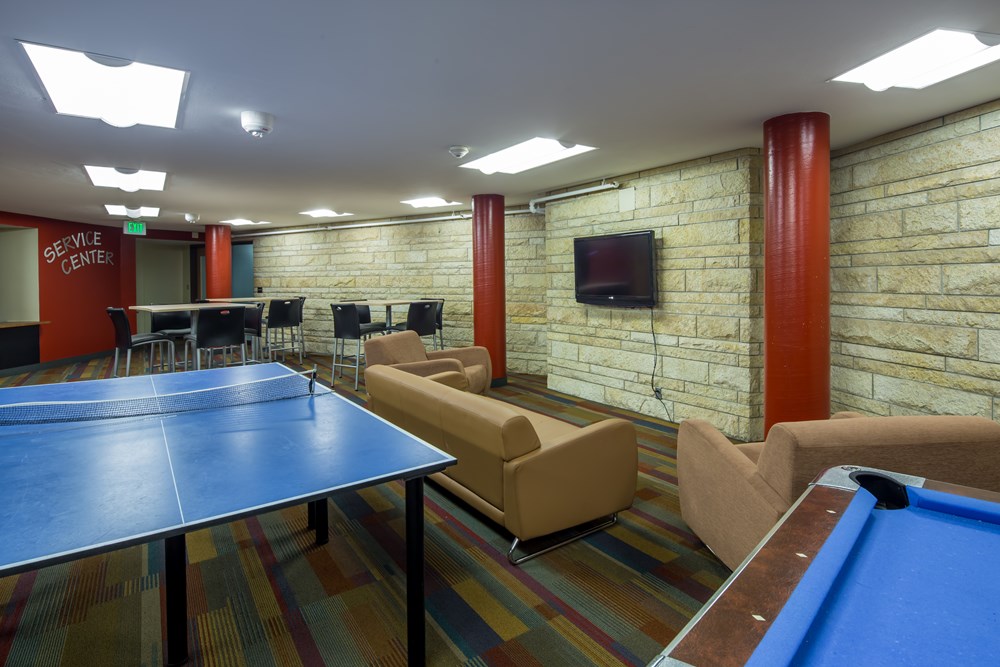 common area in a university room with seating areas, ping pong table, billard table and foosball table