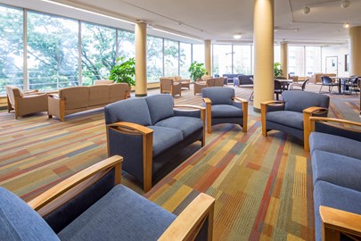 common area in a university dorm with seating areas including couches and chairs and tables with chairs