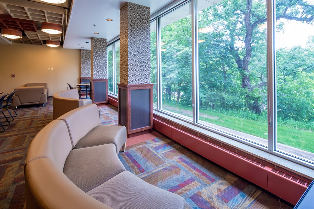 common area in a university dorm with couches facing a wall with windows
