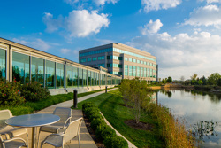 angled view of the exterior of an office building on the left and a pond on the right