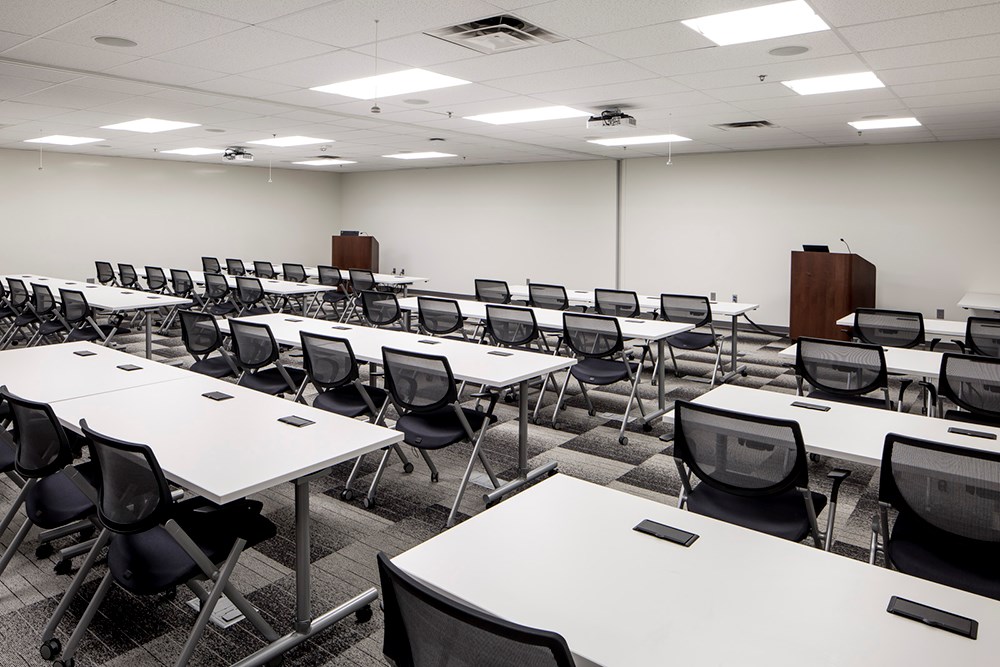 large conference room in an office building with rows of tables and chairs in the foreground and two podiums in the background