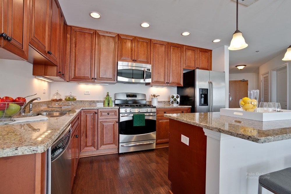 kitchen in an apartment building condo with cabinets and appliances wrapping around the room on the left and a large island with bar seating on the right