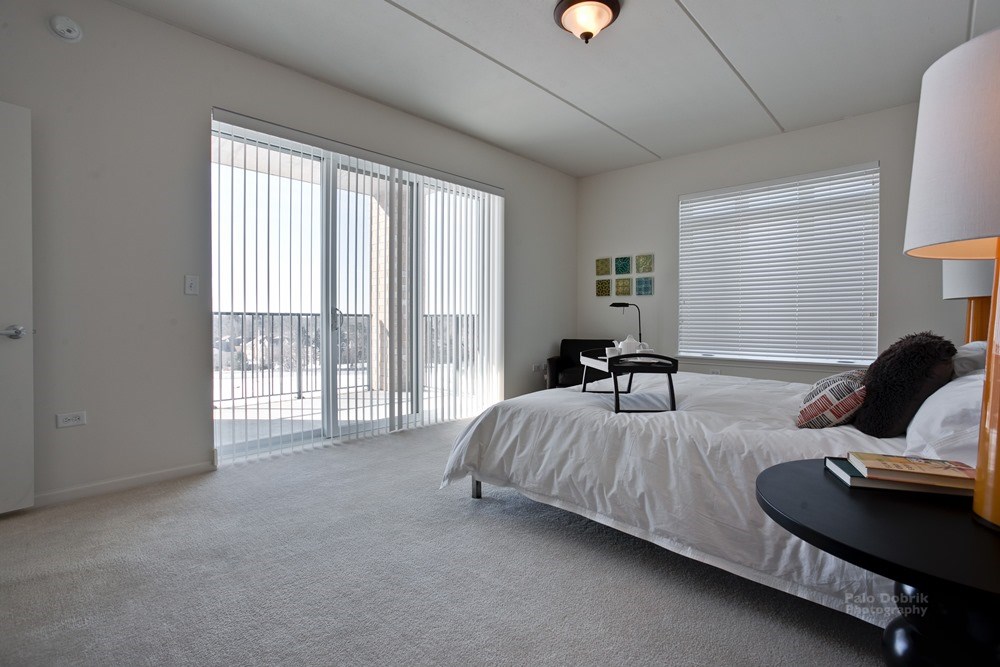 bedroom in an apartment building condo with bed on the left and sliding glass doors to the balcony on the right
