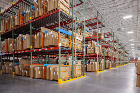 warehouse in an industrial building with rows of tall shelving filled with boxes
