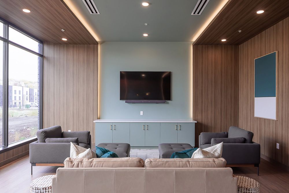 amenity area in apartment building with seating area in foreground and television mounted on the wall in background