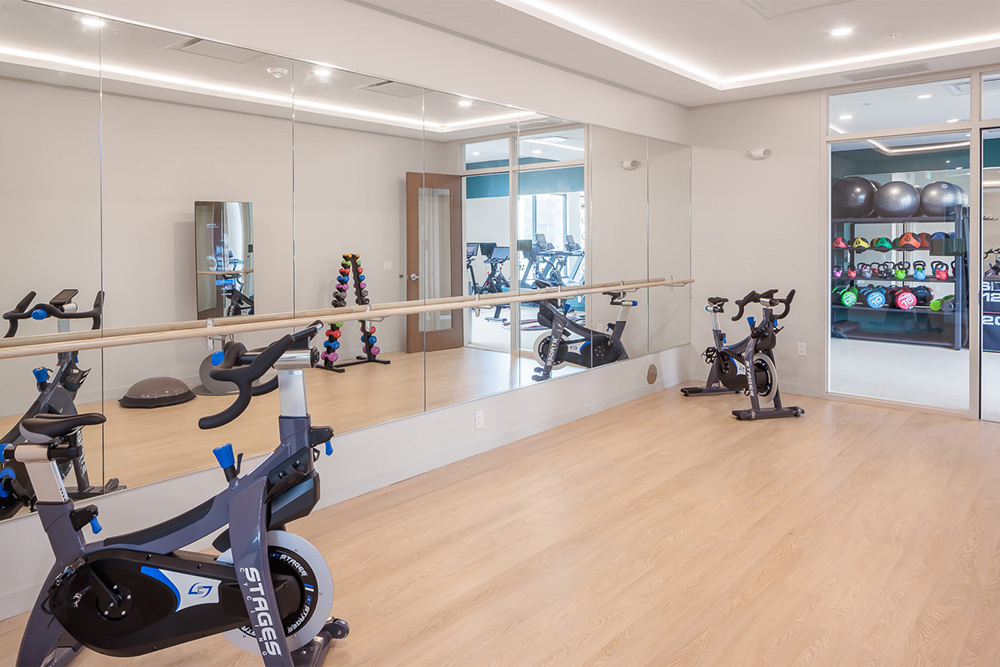 room in fitness center in an apartment building with wood floor, mirror wall and fitness equipment