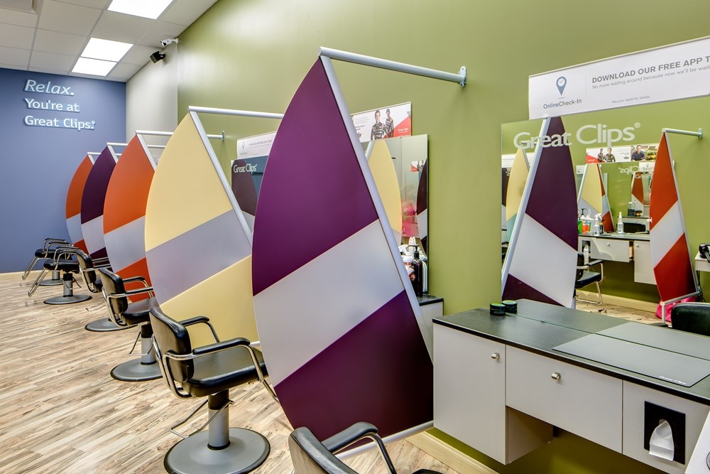 interior of a hair salon with a row of salon chairs separated by colorful half-moon privacy dividers