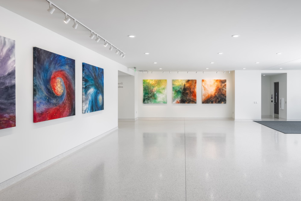 gallery space in a university building with white walls filled with brightly colored artwork