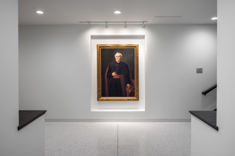 large portrait of a man on a white wall in a common area of a university building