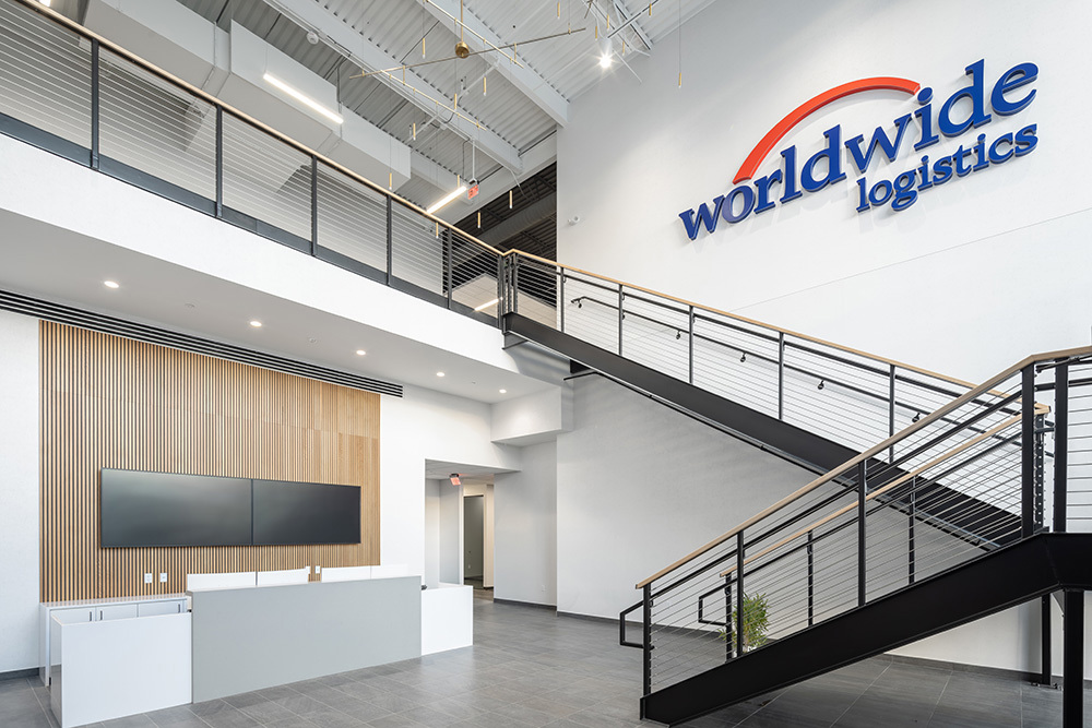 interior of office building lobby with staircase on right along wall with "worldwide logistics" sign