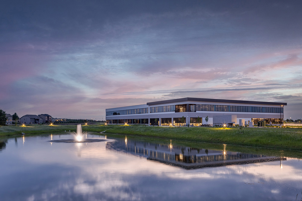 office building at sunset with pond reflecting building and cloudy sky in foreground 